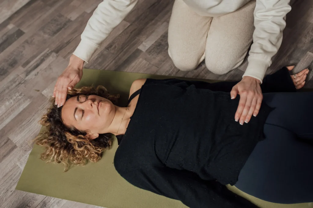 photo d'une séance de yoga thérapeutique une femme est allongée sur un tapis de yoga et reçois une séance